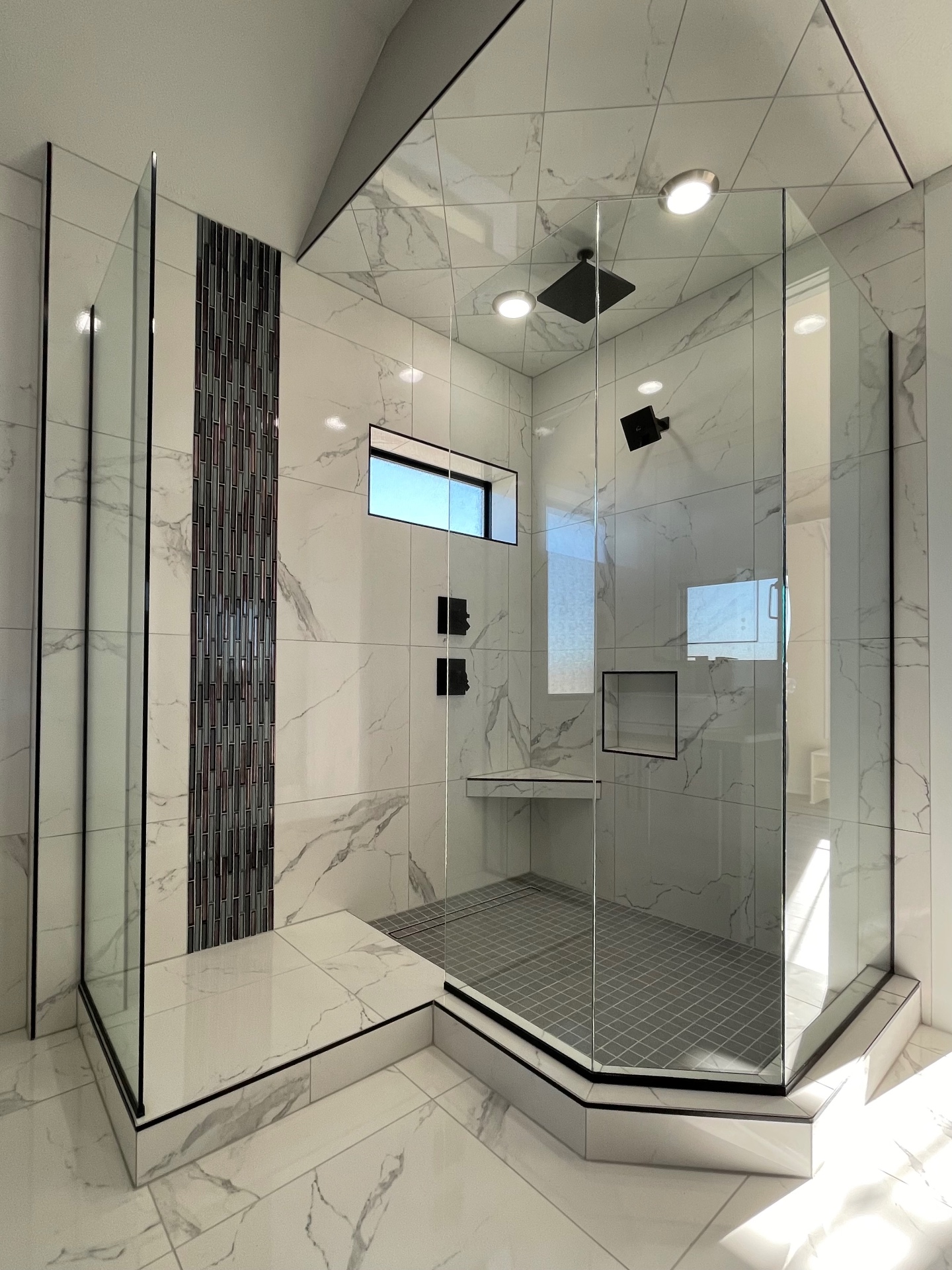 Custom frameless shower enclosure fitted beneath an angled tiled ceiling with black hardware